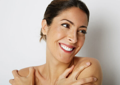 women smiling to the right side of the camera with her arms on her shoulders