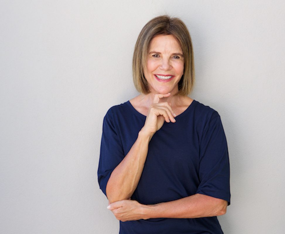 older woman smiling with hand to chin